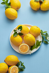 Ripe Yellow Lemons Close-up Background Or Texture. Lemon Harvest, Many Yellow Lemons. Lemons Whole and sliced placed against a blue. Lemon in a white plate