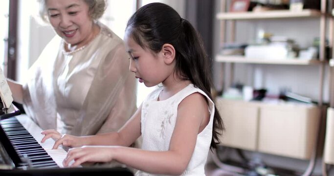 Grandmother teaching granddaughter to play the piano,4K
