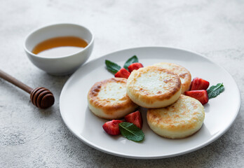 Cottage cheese pancakes, ricotta fritters on ceramic plate with  fresh strawberry.