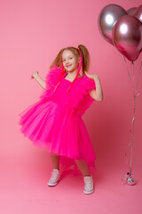 little girl on a pink background holding balloons, celebrating her birthday