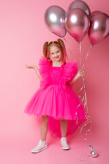 Obraz na płótnie Canvas little girl on a pink background holding balloons, celebrating her birthday
