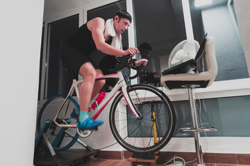 Man cycling on the machine trainer he is exercising in the home at night playing online bike racing...