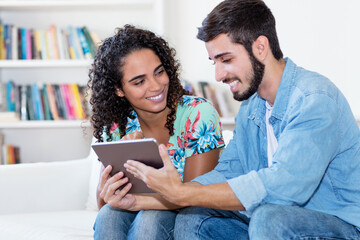 Hispanic couple reading newspaper online with tablet computer