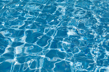 Surface of water in swimming pool on a summer day. Clear blue water and waves with re-reflection and abstract mosaics. Design element