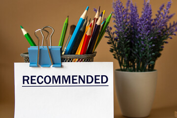 RECOMMENDED - word on a white sheet against the background of pencils and a bouquet of lavender