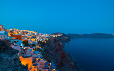 Night time blue hour view of the cliff side white cave accommodation of Oia on the Greek island of Santorini.  
