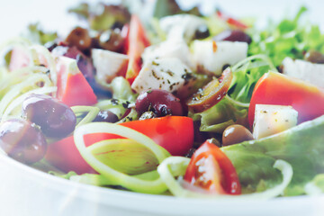 Healthy salad with feta cheese, various olives, leek and tomatoes. Close up. 