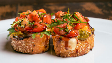 Close-up view of tomato and mozzarella bruschetta on white plate on red brick wall background. Healthy life concept.
