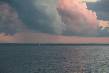 Naklejka na ściany i meble Clouds at sunset, the sea and sailboats