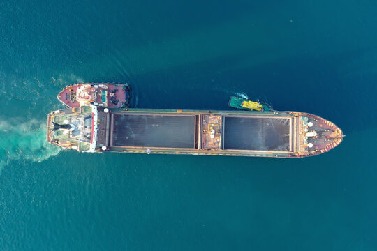 A Tug Pulls A Cargo Ship In The Port. View From Above. Shooting From A Drone. 