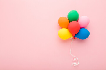 Heap of colorful balloons with white ribbon on light pink table background. Pastel color. Congratulation concept. Empty place for inspirational, emotional text, lovely quote or sayings. Top down view.