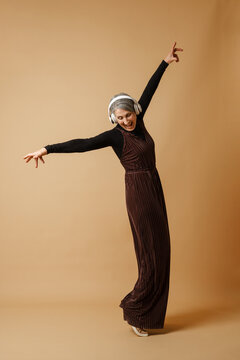 Grey senior woman dancing while listening music with headphones