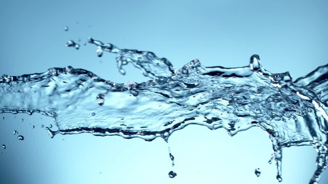 Super slow motion of flying water splashes in collision, blue background. Filmed on high speed cinema camera, 1000fps.