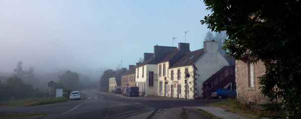 village along road in central brittany on early foggy morning