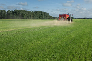 Fertilizer spreader. Fertilizer. Tractor. Farming. Meadow. Grass. Chalk. Netherlands