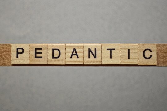 text the word pedantic from gray wooden small letters with black font on an gray table
