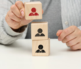 female hand holds a wooden cube with a man. The concept of finding a leader, a talented employee,...