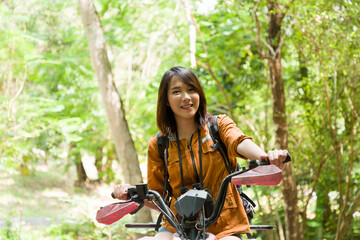 Fototapeta na wymiar Asian young woman driving off road adventure with happy and smiling. Asian woman riding on ATV bike or quad bike on road along forest trail on mountain. Camping, jungle adventure concept