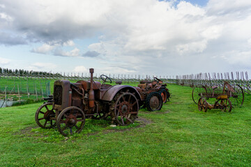 row of old rusted and historic tractors and farm machines in a field