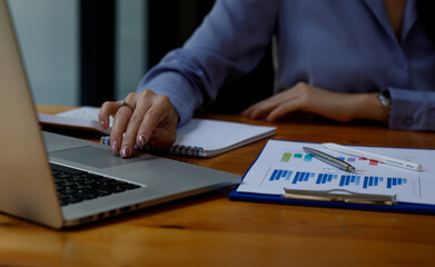 Close up of woman working on project for analyzing company financial report balance statement with documents graphics at modern office. business,economy, market,money and tax concept .