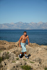 a young guy is walking along a rocky beach near the sea