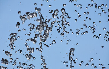 Water drops of fountain stream over blue sky