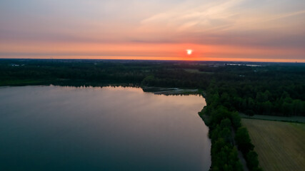 Sunset sky background. Dramatic red and gold sunset sky with evening sky clouds over the forest lake. Stunning sky clouds in the sunset. High quality photo