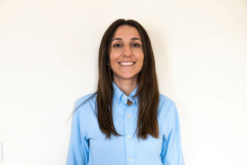 Young and attractive woman looking corporative with a shirt smiling at the camera, looking professional and ready to do bussiness with a white background. Wearing a blue shirt. Latin woman business.