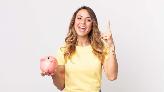pretty thin woman feeling like a happy and excited genius after realizing an idea and holding a piggybank