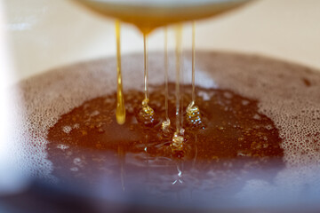 Drop of bee honey drip from hexagonal honeycombs