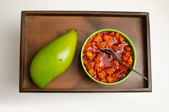 Raw Mango and Kairi and Mango Pickle Achar placed on a wooden Tray Studio Shot