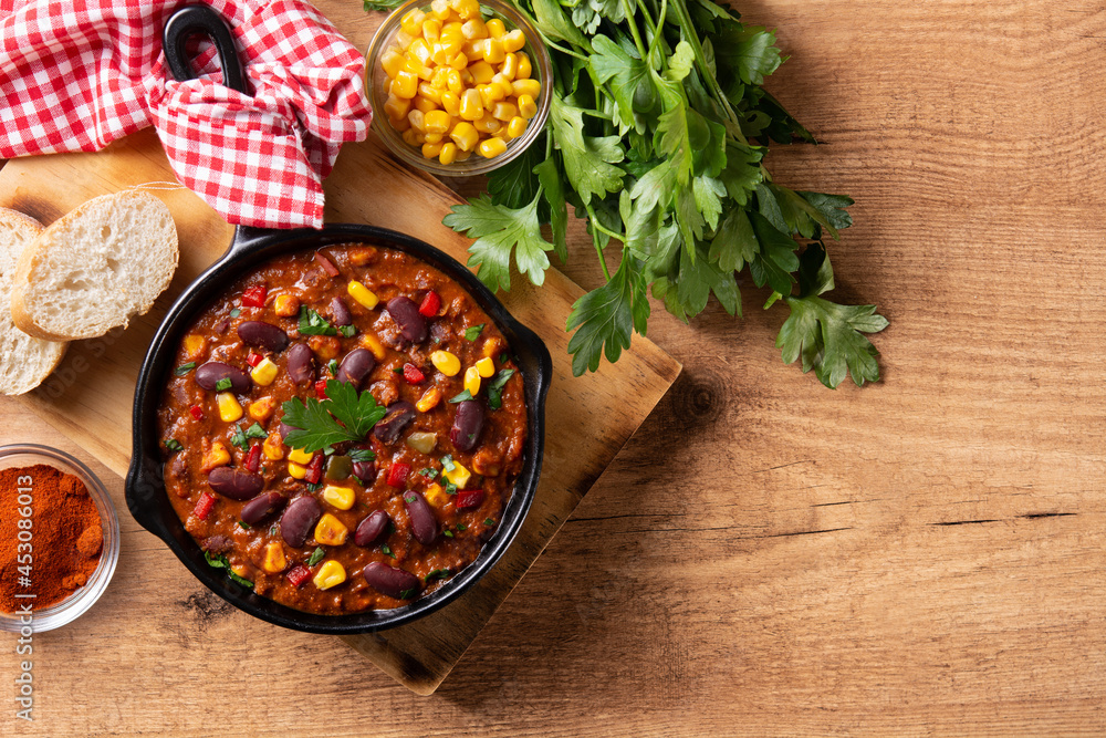 Wall mural Traditional mexican tex mex chili con carne in iron pan on wooden table