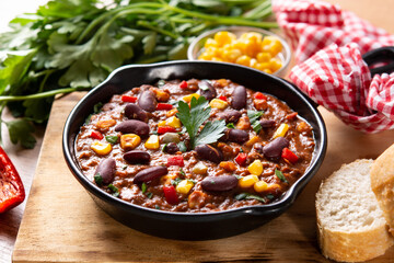 Traditional mexican tex mex chili con carne in iron pan on wooden table