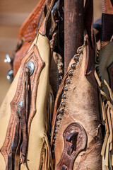 Cowboy chaps hanging on a fence with focus on decorative detail and copy space