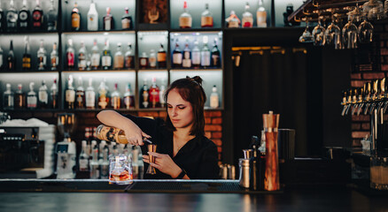 Portrait of young attractive woman bartender Making Cocktail in bar
