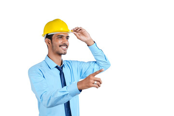 Young Indian engineer wearing yellow color hard hat and giving successful gesture.
