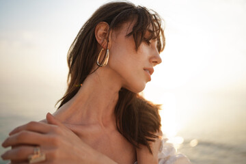 Portrait of young brunette haired woman at the beach at sunset