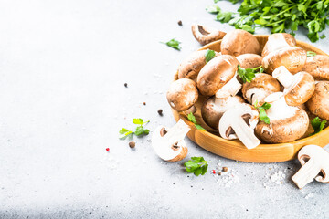 Raw mushrooms Champignon in wooden bowl with spices and herbs for cooking.