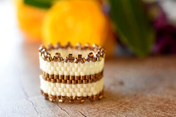 Golden and white beaded ring on a wooden surface