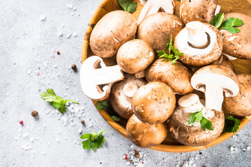 Champignon. Fresh organnic mushrooms in wooden bowl ready for cooking. Top view with copy space at light table.