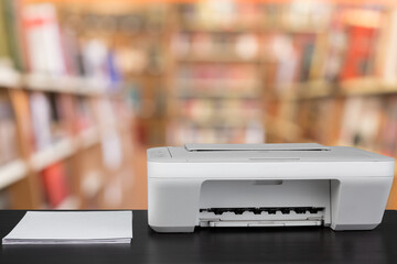 Compact laser printer on black desk against blurred background