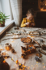 A cute sweet girl makes Christmas decorations from dried oranges, twigs and cones. Crafts for the holiday