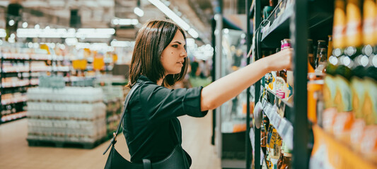 Young woman choosing beer in a supermarket