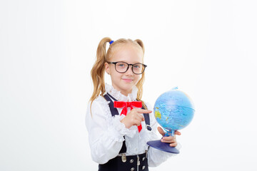 a little schoolgirl girl in a school uniform holds a globe isolated on a white background