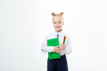 a little schoolgirl girl in a school uniform holds a book isolated on a white background