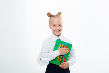 a little schoolgirl girl in a school uniform holds a book isolated on a white background