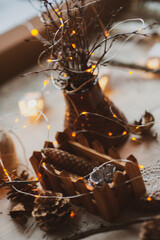 Christmas New Year. A vase with dry branches decorated with a luminous garland. Decor elements all around: cones, dry oranges. New year holiday, celebration concept.