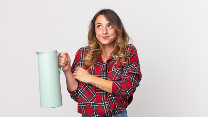 pretty thin woman shrugging, feeling confused and uncertain and holding a coffee thermos