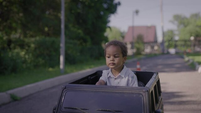 Cute African American boy in a toy car. Boy and rides in the park.