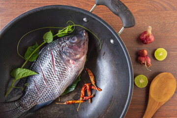 Fresh fish in a pan and spices to cook